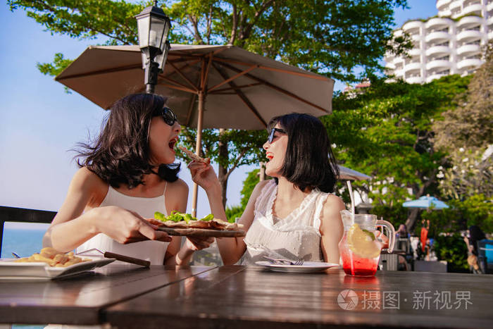 休闲概念美丽的女孩正在海边餐馆吃饭美丽的女孩正在享受桌子上的食物