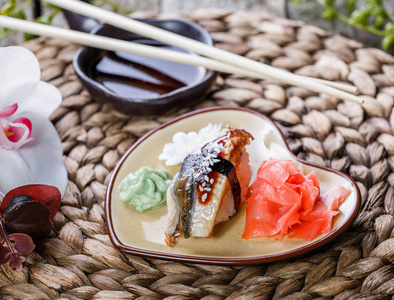 寿司套装Nigiri和寿司卷装饰着竹子背景上的花。 日本料理。 选择性聚焦