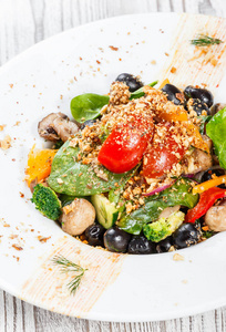 蔬菜沙拉与菠菜，蘑菇，西红柿，洋葱，黄瓜，西兰花，橄榄和坚果在盘子上的轻木制背景。 健康的食物。 顶部视图