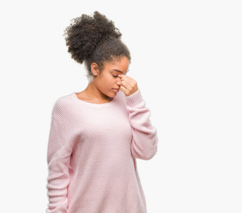年轻的非洲美国女人穿着冬天的毛衣，在孤立的背景下疲惫地鼻子和眼睛，感到疲劳和头痛。 压力和挫折的概念。