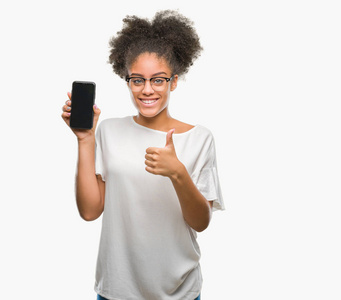 年轻美丽的美国黑人显示智能手机屏幕在孤立的背景上，快乐的大微笑，做好的，用手指签署拇指，优秀的标志。