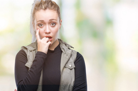 年轻的金发女人在孤立的背景上看起来压力和紧张，双手咬着嘴的指甲。 焦虑问题。