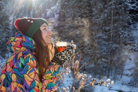 女孩喜欢雪落。在一次降雪过程中，森林正在喝茶了针织的形状的年轻女子。健美的照片