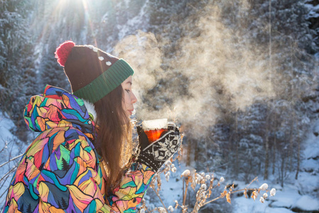女孩喜欢雪落。在一次降雪过程中，森林正在喝茶了针织的形状的年轻女子。健美的照片