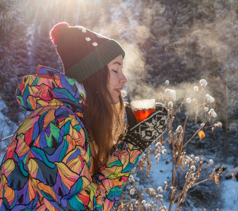 女孩喜欢雪落。在一次降雪过程中，森林正在喝茶了针织的形状的年轻女子。健美的照片