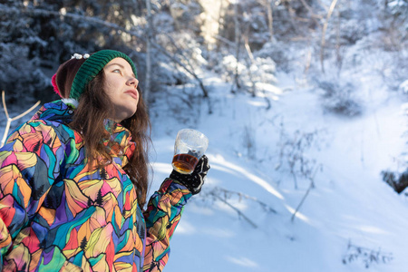 女孩喜欢雪落。在一次降雪过程中，森林正在喝茶了针织的形状的年轻女子。健美的照片