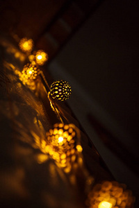 喜庆的花环雕刻金属碗是从里面用金色的光点燃的。带有插槽的青铜球圣诞灯，营造节日气氛