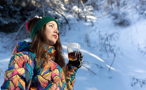 女孩喜欢雪落。在一次降雪过程中，森林正在喝茶了针织的形状的年轻女子。健美的照片