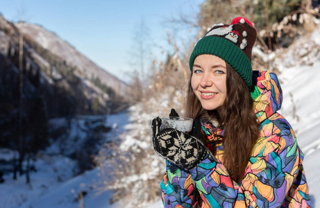 女孩喜欢雪落。在一次降雪过程中，森林正在喝茶了针织的形状的年轻女子。健美的照片