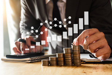 商人拿着硬币,用智能手机和计算器来计算概念,为财务会计省钱照片