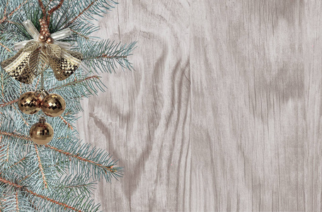 圣诞节和新年的节日背景是绿杉树的树枝，金色的圣诞钟声，球，雪花和丝带在木制表面，有文字空间
