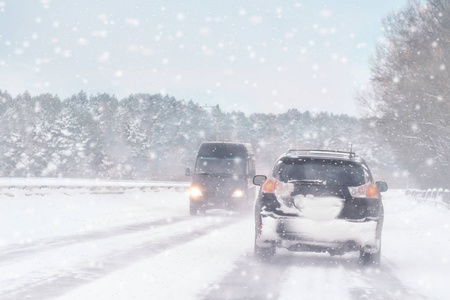 冬季暴风雪在道路上能见度差。 汽车在暴风雪中开着头灯