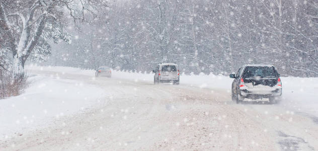 冬季暴风雪在道路上能见度差。 汽车在暴风雪中开着头灯