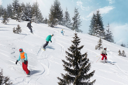 一群快乐的朋友滑雪板和滑雪者骑在滑雪坡上玩得很开心。