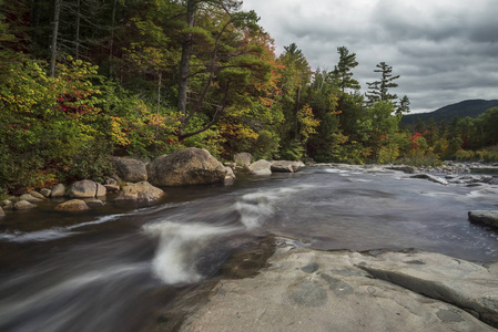 河流在森林中的石岸之间流淌。 弗兰科尼亚缺口州立公园。 美国。 新罕布什尔州。