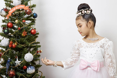 圣诞快乐，节日快乐，可爱的小孩，亚洲女孩正在室内装饰圣诞树。