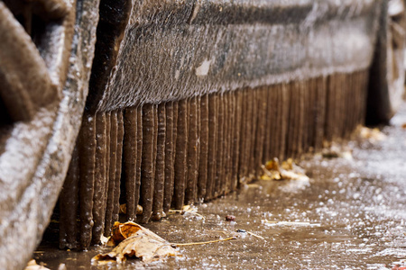 冬天，站在一个肮脏的水坑附近的汽车门阶上的脏冰柱解冻了