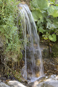 一个小瀑布从山上流动在一个阳光明媚的夏天地区tzoumerka希腊山平多斯。