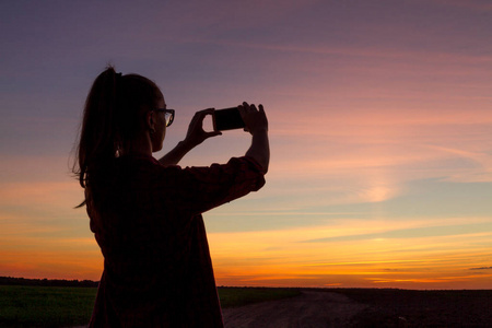 一个旅游女孩旅行并拍摄傍晚日落的照片。复制空间