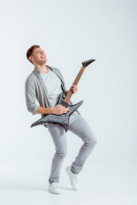 穿灰色衣服的兴奋男人在灰色背景下弹电吉他
