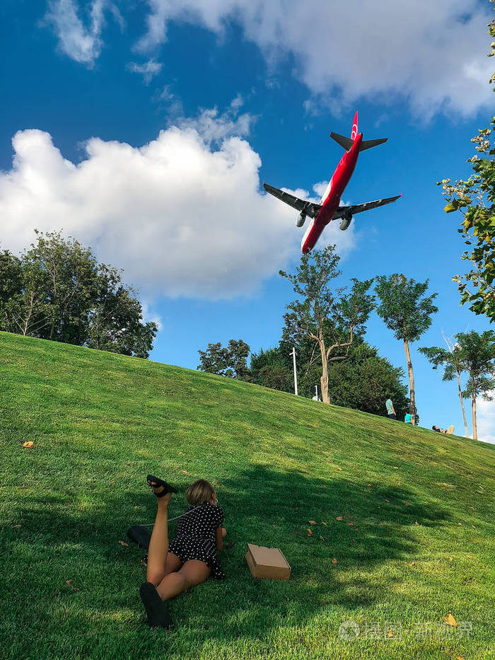 躺在草地上看飞机的年轻女子
