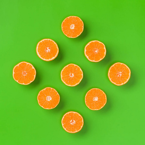 绿色背景上新鲜橙色切片的水果图案。 平躺顶部视图。 流行艺术设计创意暑期概念。 一半的柑橘在最小的风格。