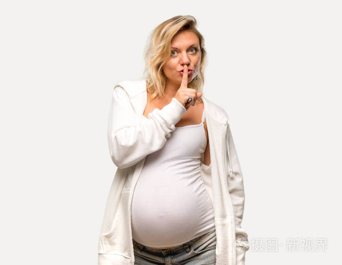 怀孕的金发女子，穿着白色运动衫，在孤立的灰色背景上表现出闭上嘴和沉默的手势