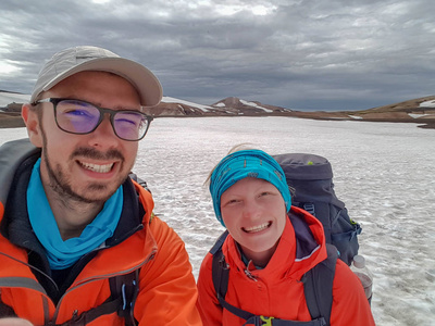 快乐的年轻夫妇，男人和女人一起在山上徒步旅行，在冰岛带着沉重的背包。 旅行冒险流浪活跃生活方式概念