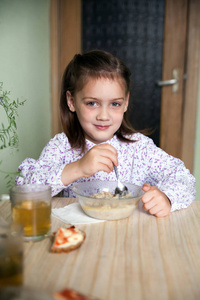 小女孩坐在厨房里吃燕麦片。