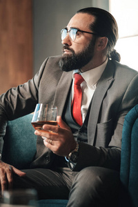 商人穿着红色领带喝威士忌玻璃图片