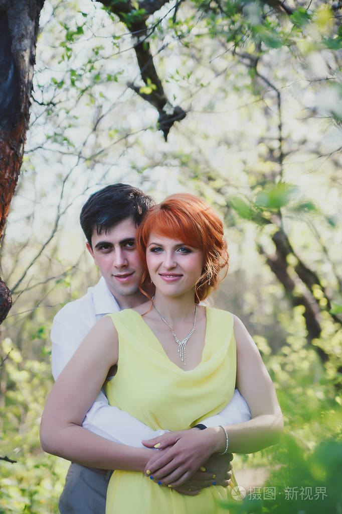 美丽的已婚夫妇在开花花园的背景下的肖像