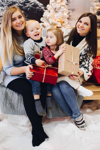 两个母亲坐在可爱的孩子和举行圣诞礼物