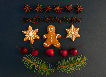 圣诞装饰背景与姜饼饼干。 云杉枝香料和苹果在黑石板上。