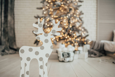 装饰鹿在圣诞树的背景上，有礼物和装饰品。