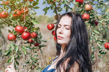 野生苹果园里的深色头发。 背景上的肖像苹果分公司。 女性的。 夏天的记忆。 时尚前夜。 自然自然自然