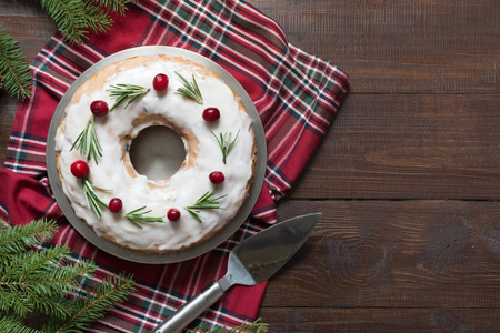 传统自制圣诞蛋糕装饰蔓越莓浆果和迷迭香在盘子和木板上。 用糖霜粉化。