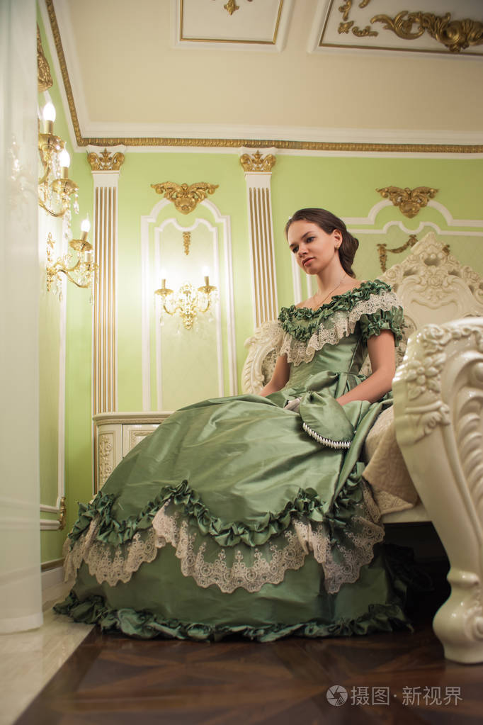 复古巴洛克时尚女性肖像,穿绿色复古礼服在旧宫室内