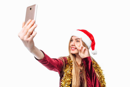 戴着圣诞帽和连衣裙的快乐女人，在智能手机上。在白色背景上