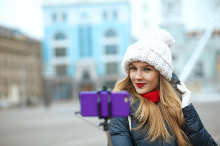 令人高兴的金发女游客戴着针织帽，在冬天在街上自拍。 文本空间