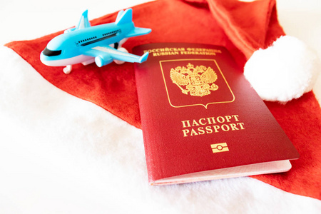 俄罗斯国际护照蓝色玩具飞机和白色背景的红色圣诞老人帽。