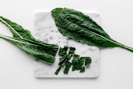 有机绿羽衣甘蓝叶子在大理石板上白色桌子背景健康烹饪营养概念顶部视图