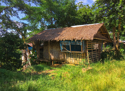 空的废弃的小屋或平房，在明亮的绿色热带森林有一个由棕榈树叶和竹墙组成的茅草屋顶。 菲律宾典型的住房和出租给游客