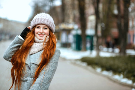 城市肖像快乐红头模特长发，穿着温暖的衣服在城市散步。 文本空间