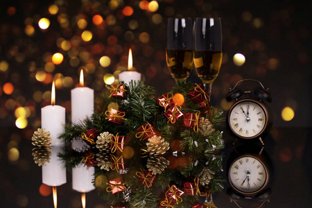 两个酒杯，香槟，时钟，蜡烛和圣诞装饰在黑色背景与反射。复制空间。圣诞快乐，新年快乐