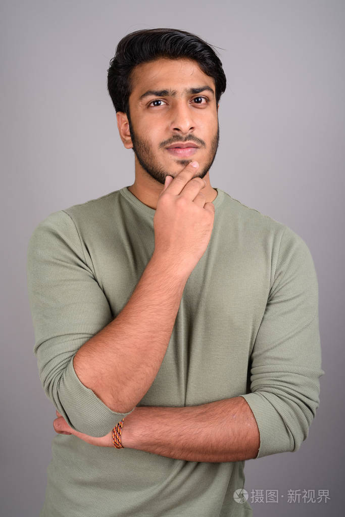 年轻英俊的印度男人的画像在灰色背景