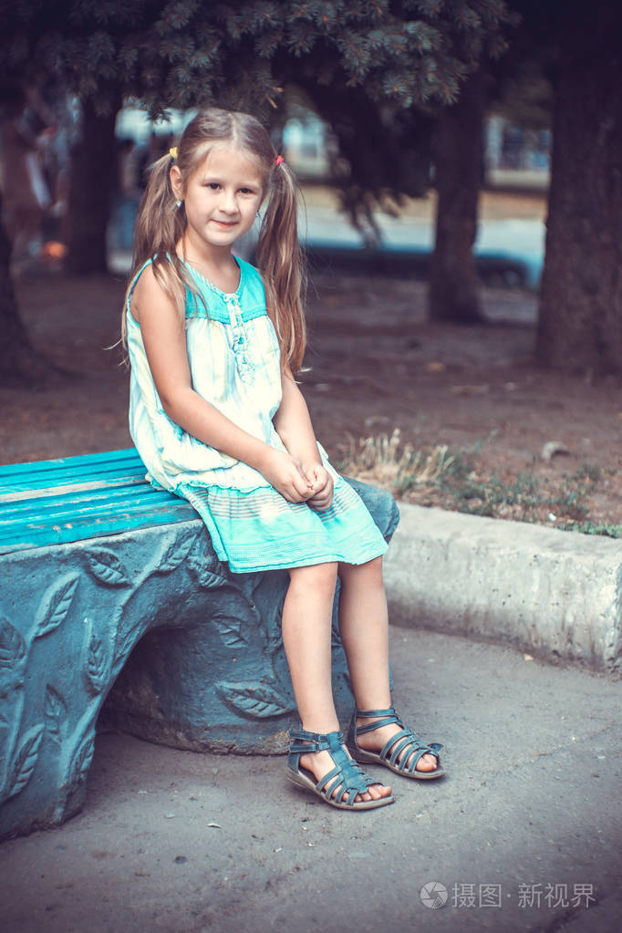 夏天公园里一个小女孩在长凳上的肖像