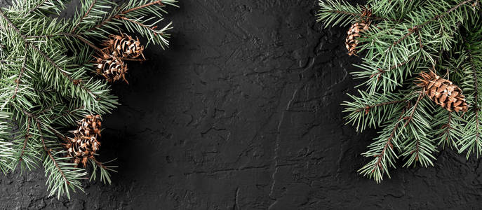 创意布局框架由圣诞树树枝松果在黑暗的背景。 圣诞节和新年主题。 雪。 平躺顶部视图空间文本
