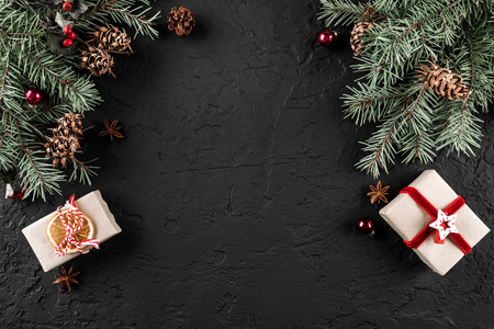 创意布局框架由圣诞树树枝松果礼物在黑暗的背景。 圣诞节和新年主题。 雪。 平躺顶部视图空间文本