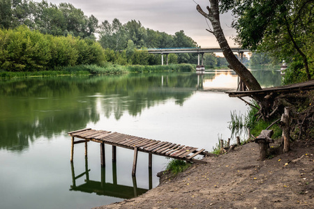 夏天在平静的河流上码头。 上午的木墩桥。 在河里钓鱼的地方。 色调风格的照片