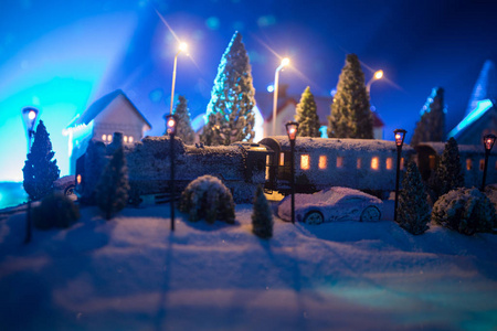 冬季场景的缩影，有圣诞屋火车站树木积雪。夜景。新年或圣诞节的概念。选择性聚焦